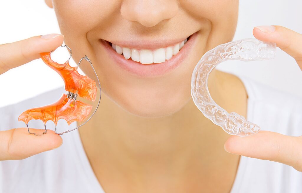 Nose-to-neck view of woman holding two kinds of retainers