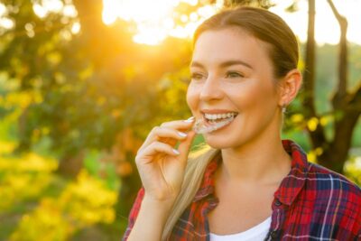 Woman inserting Invisalign aligner into her mouth.