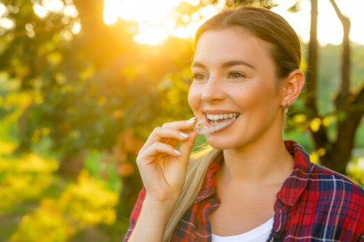 Woman inserting Invisalign aligner into her mouth.
