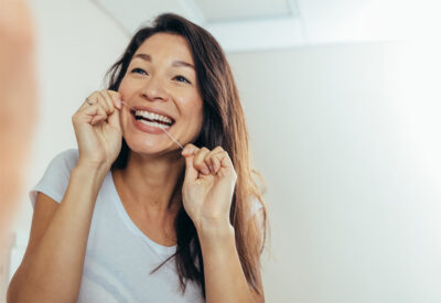 Woman smiling while flossing teeth.