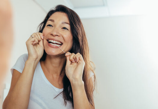 Woman smiling while flossing teeth.