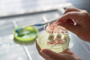Hand holding retainer above its case. 